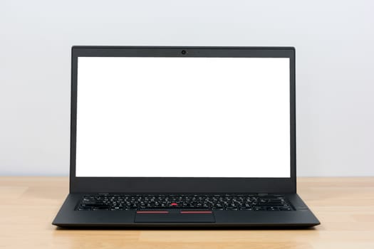 Black laptop on wooden table on white wall