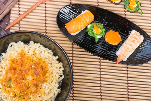 sushi and noodle in black dish on wooden background