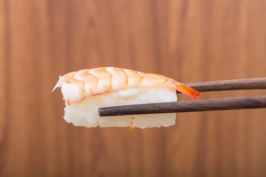 Sushi roll with black chopsticks on wooden background