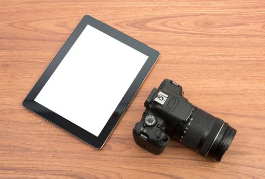 DSLR digital camera and tablet on wooden dask table