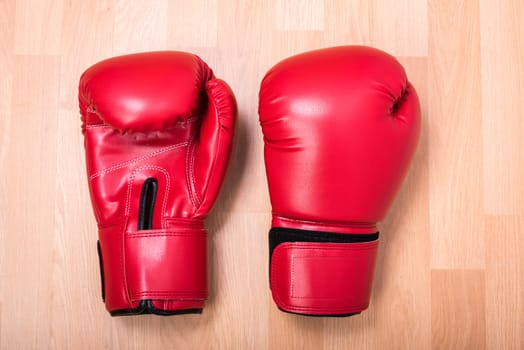 Two red boxing gloves on wooden table