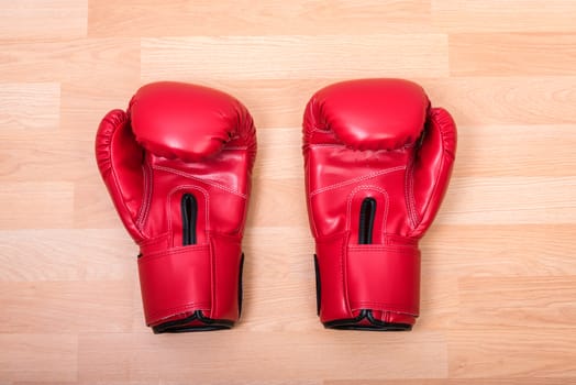 Two red boxing gloves on wooden table
