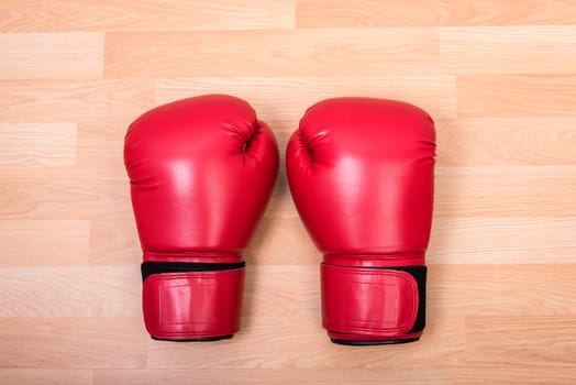 Two red boxing gloves on wooden table