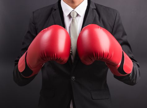 Young businessman with boxing gloves isolated on black background