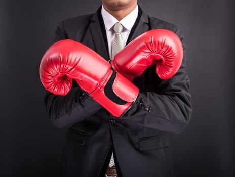 Young businessman with boxing gloves isolated on black background
