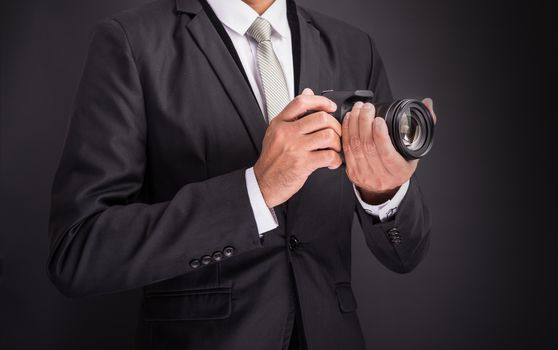 Young photographer man holding camera isolated on black background