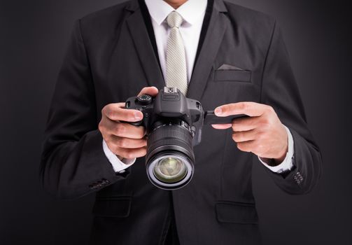 Young photographer man holding camera isolated on black background