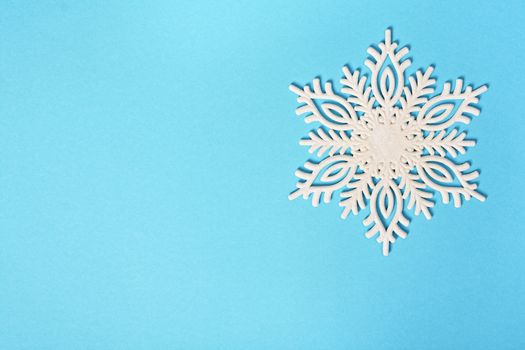 Christmas or winter composition. White glittery snowflake on pastel blue background. Christmas, winter, new year concept. Flat lay, top view, copy space.