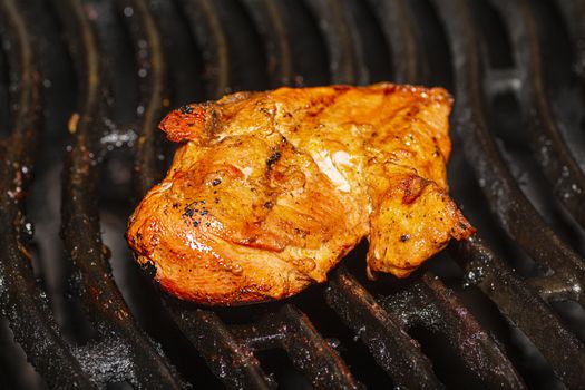 Marinated orange chicken breast on a black BBQ grill