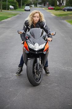young blond woman, on a sport motocycle, ready to leave on a ride