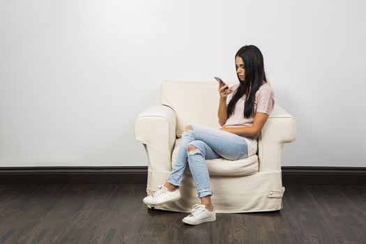 Young woman sitting on a couch looking at her phone
