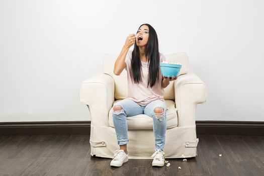 young millennial girl eating a handful of popcorn