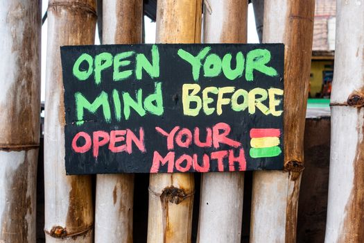 Handmade painted sign reads open your mind before open your mouth