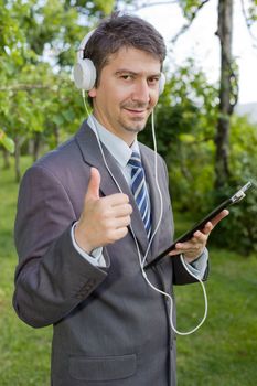 happy businessman with digital tablet and headphones, outdoors