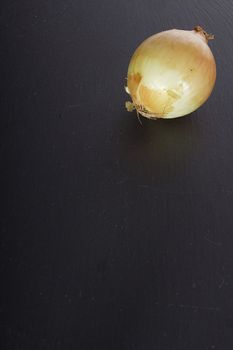 Ripe onion in husk on a black stone cutting board