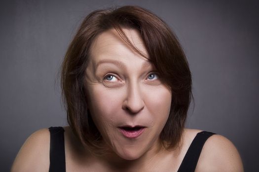 Woman grimaces in front of camera on black background