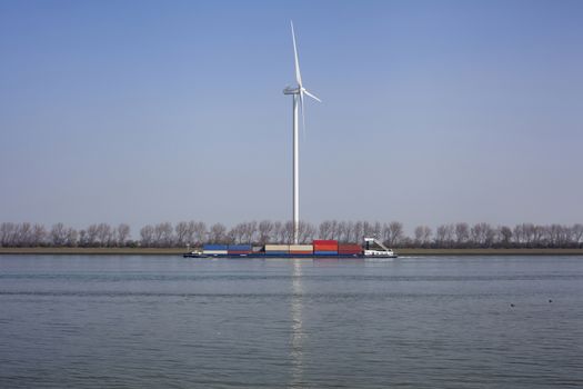 Netherlands, New Waterway. Container ship in front of modern windmill shipping, transport and heavy industry nera Maasvlakte 2.