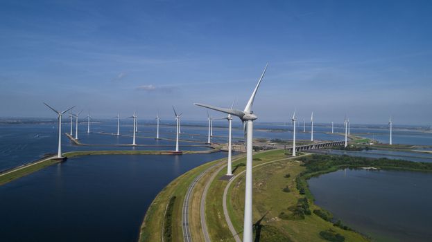 A Modern Wind Farm consisting of Wind Turbines with Two and Three Blades along the Shore of Grevelingenmeer under a Blue Sky in the Netherlands