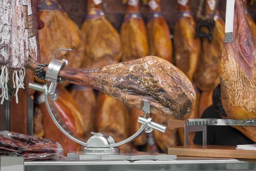 Spanish Jamon Serrano on steel table in a markethall. Valencia, Spain