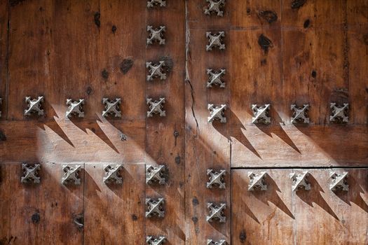 Sunshine on traditional old wooden door. Use of nails and metal at the old wooden door