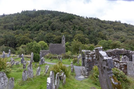 Ancient Celtic gravesite with unmarked gravestones and old rundown church in ireland