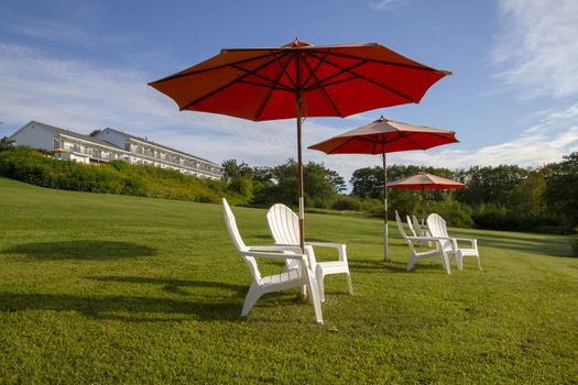 plastic chairs and umbrella on grass in the sun and blue sky
