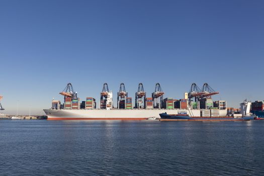 Large harbor cranes loading container ships in the port of Rotterdam, Netherlands