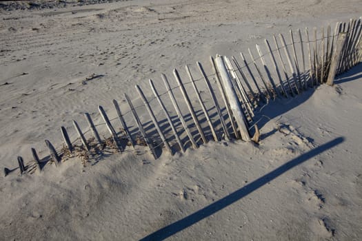 a rundown fench covered with sand in the foreground