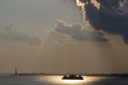 Ferry cruises past the Statue of Liberty on a sunset. Manhattan, New York City, USA