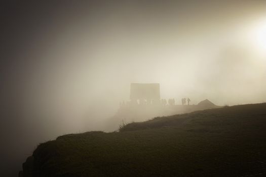 Tourist at Machu Picchu at sunrise in the fog