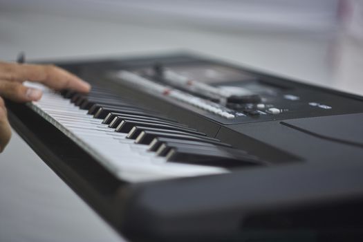 Hand of a musician pressing the keys of an electronic keyboard while playing at a concert