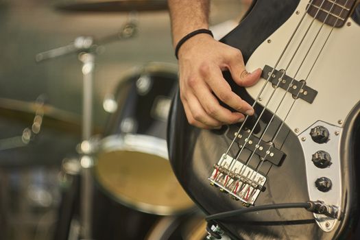 Detail of a bass player who plays his eacoustica bass at a live rock music concert.