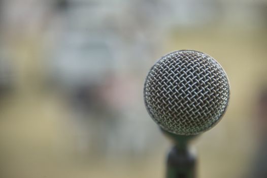 Detail of a microphone for singing taken in front view (view of the singer) with the background completely blurred. Useful as a graphical resource.