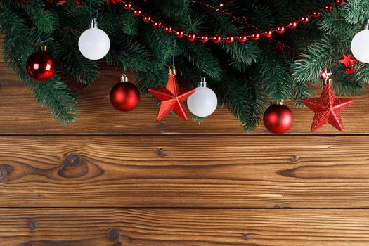 Christmas decoration frame on wooden background, fir tree branch, red and white baubles