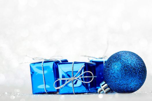 Decorative Christmas ball and gifts on abstract glitter silver background