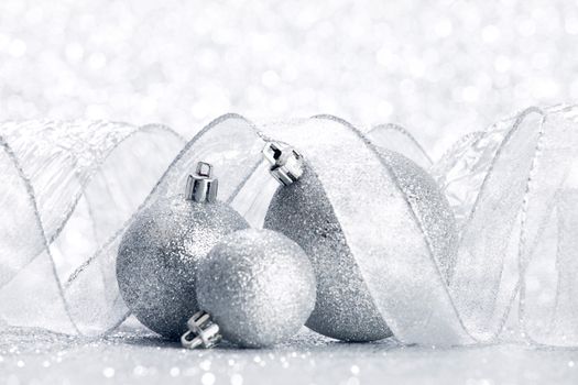 Christmas decorative balls and ribbon on silver glitter background