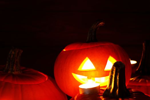 Group of Halloween pumpkin head jack o lantern and candles on dark wooden background