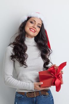 Young happy woman in santa hat holding christmas gift box