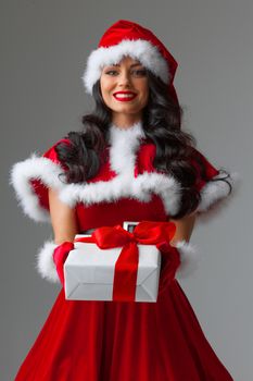 Woman in red Santa Claus outfit holding christmas gift box