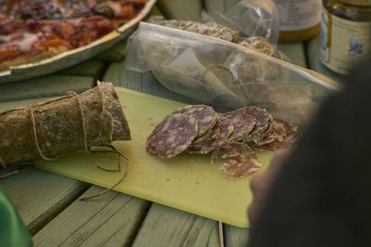 Table with chopping board and a sliced salame ready to be eaten. Salame, sausage, typical recipe of northern Italy.