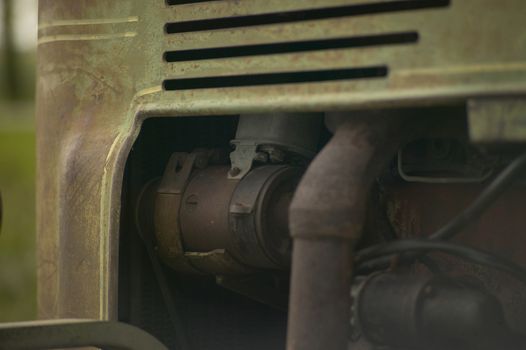 Detail of the engine with its components, including the starter, in view of an old used and rusty vintage tractor used in agricultural machining. Like once.