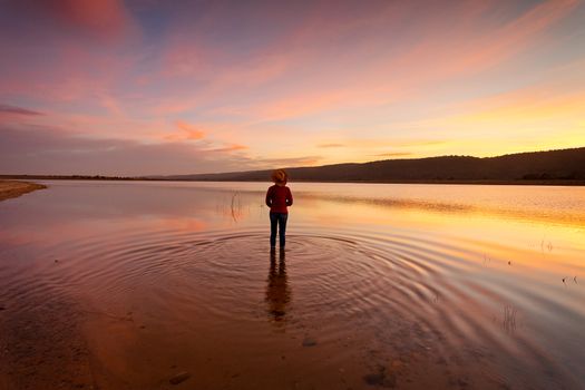 A person quietly watching with awe and wonder the sunset and its magnificent reflections in the water in rural Australia