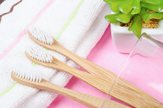 Bamboo toothbrushes in glass with towel. Eco friendly concept.