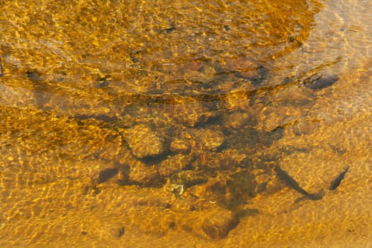 
The bottom of the lake is yellow strewn with pebbles and sand.