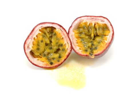 Passion fruit cut in half to reveal juicy yellow pulp around seeds, on a white background