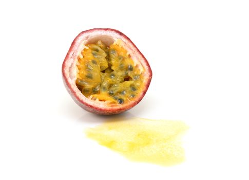 Half a purple passion fruit in cross section, showing sweet yellow pulp with seeds and spilled juice, on a white background