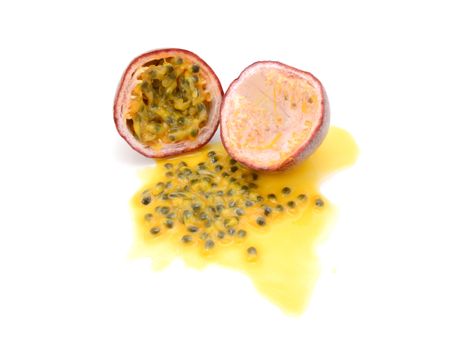 Half passion fruit with sweet pulp, seeds and juice spilled from the other half, on a white background