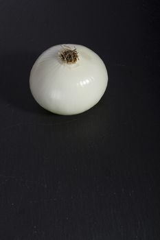Ripe onion on a black stone cutting board