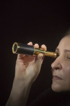 Woman looking through spyglass on black background