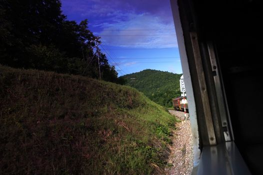 View from train window in motion of countryside and sky on sunny warm , in Thailand , Effect saturation
